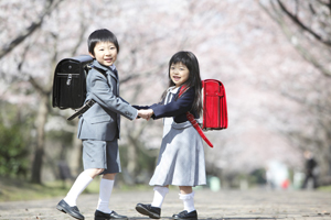 桜並木を歩く小学生男女